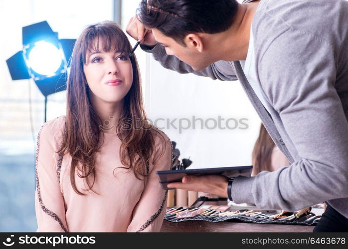 Man doing make-up for cute woman in beauty salon