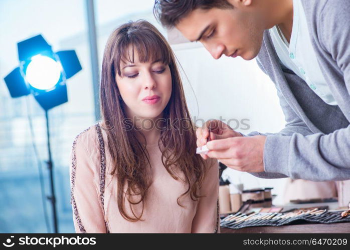 Man doing make-up for cute woman in beauty salon