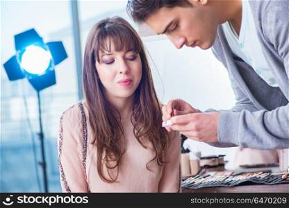 Man doing make-up for cute woman in beauty salon