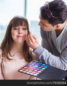 Man doing make-up for cute woman in beauty salon. The man doing make-up for cute woman in beauty salon
