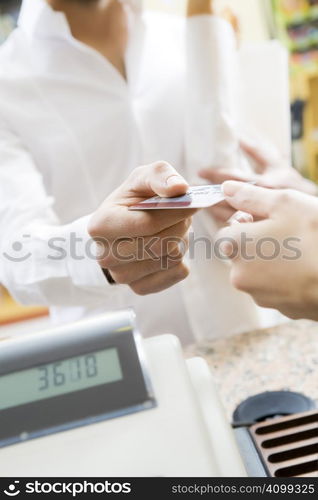 man doing shopping in a grocery store and paying by credit card