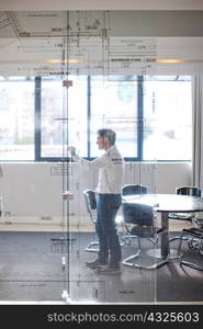 Man drawing architectural plans on glass wall