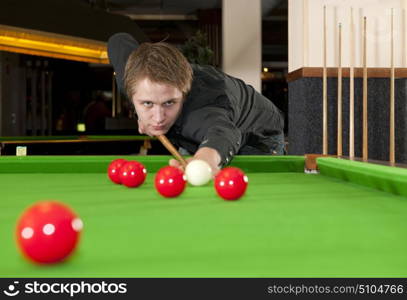 Man, dressed in a black shirt, playing snooker