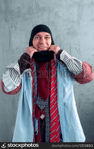 Man dressed in many clothes trying on a balaklava at the clothing store. Shopping concept