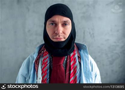 Man dressed in many clothes trying on a balaklava at the clothing store. Shopping concept. Man trying on a balaklava at the clothing store