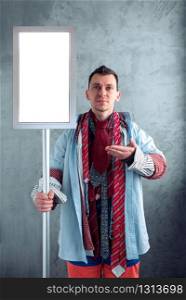 Man dressed in many clothes with empty sign in hand. Clothing sale concept. Advertising signboard