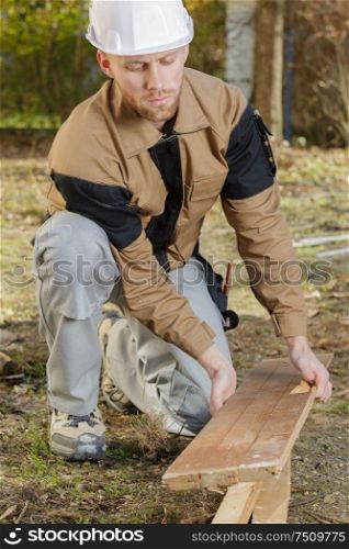 man drilling and measuring wood for deck