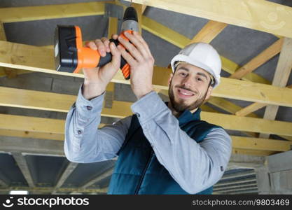 man drills the wooden ceiling plank