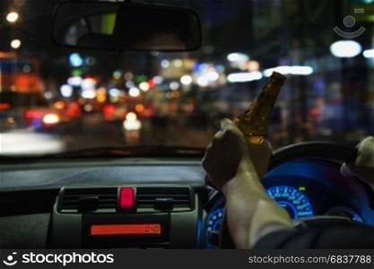 Man drink beer while driving at night in the city dangerously, left hand drive system