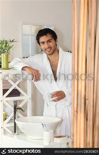 Man drinking a glass of water in his bathroom