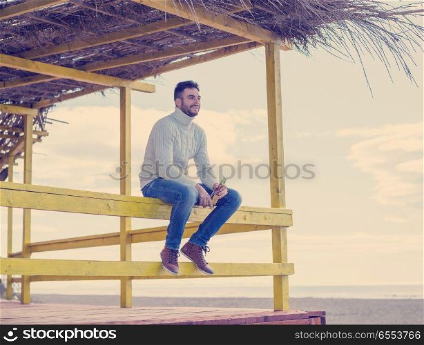 Man Drinking Beer on beach during autumn time. man drinking beer at the beach