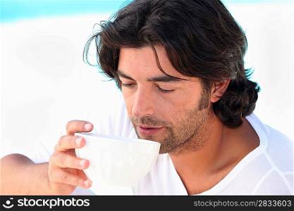 Man drinking coffee by swimming pool