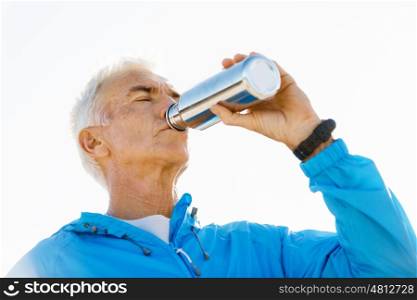 Man drinking from a sports bottle. Handsome healthy man in sport wear drinking from sports bottle
