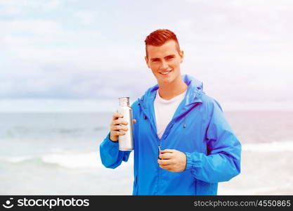 Man drinking from a sports bottle. Young man in sport wear drinking from sports bottle