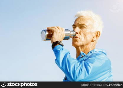 Man drinking from a sports bottle. Young man in sport wear drinking from sports bottle