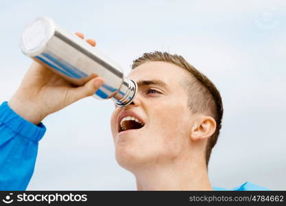 Man drinking from a sports bottle. Young man in sport wear drinking from sports bottle