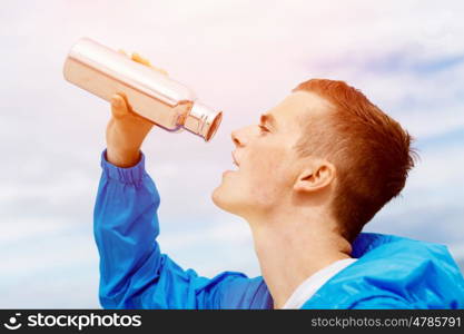 Man drinking from a sports bottle. Young man in sport wear drinking from sports bottle