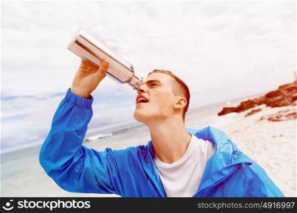 Man drinking from a sports bottle. Young man in sport wear drinking from sports bottle