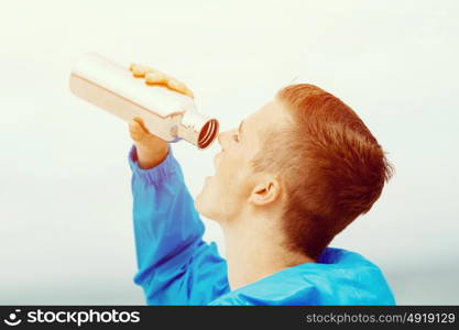 Man drinking from a sports bottle. Young man in sport wear drinking from sports bottle