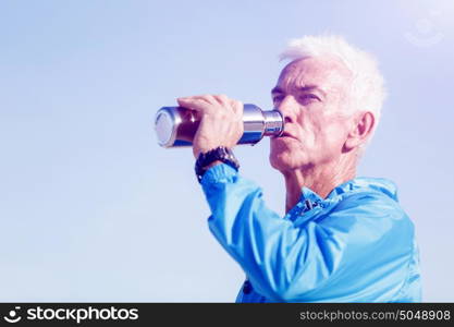 Man drinking from a sports bottle. Young man in sport wear drinking from sports bottle