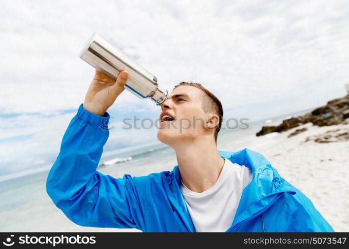 Man drinking from a sports bottle. Young man in sport wear drinking from sports bottle