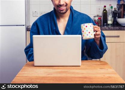 Man drinking from cup and working on laptop