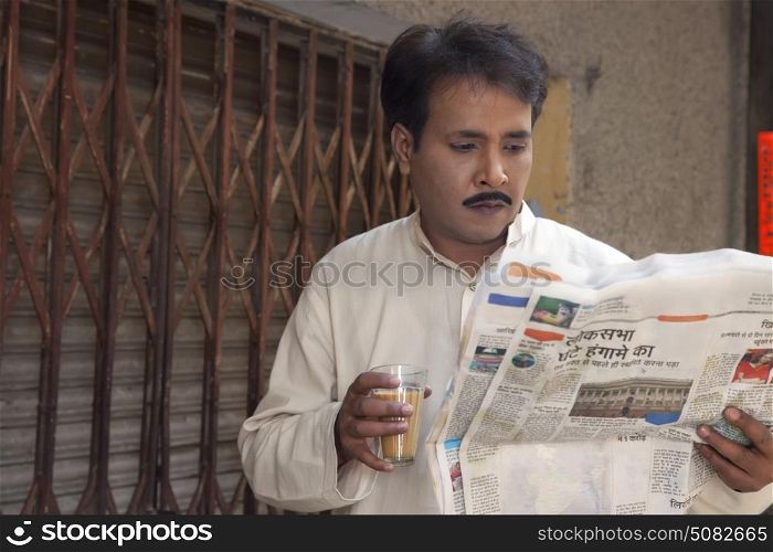 Man drinking tea and reading a newspaper