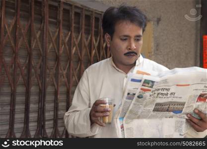Man drinking tea and reading a newspaper