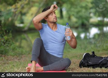 man drinking water after workout outdoors