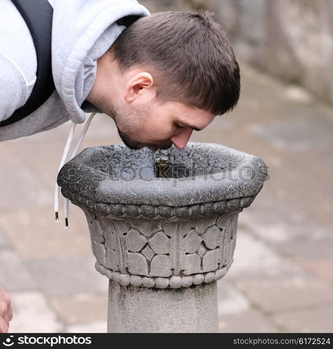 Man drinking water from fountain at street