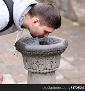 Man drinking water from fountain at street