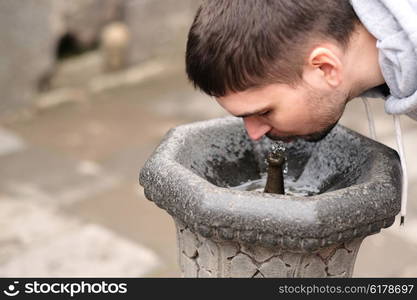 Man drinking water from fountain at street