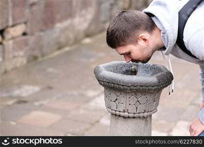 Man drinking water from fountain at street