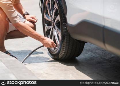 man driver hand inflating tires of vehicle, removing tire valve nitrogen cap for checking air pressure and filling air on car wheel at gas station. self service, maintenance and safety