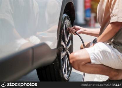 man driver hand inflating tires of vehicle, removing tire valve nitrogen cap for checking air pressure and filling air on car wheel at gas station. self service, maintenance and safety