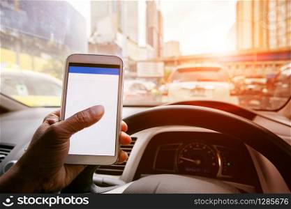 man driving car in urban traffic and touching on smart phone application screen