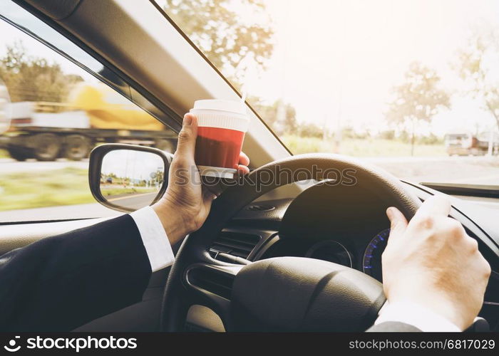 Man driving car while holding a cup of coffee