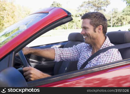 Man driving convertible car smiling