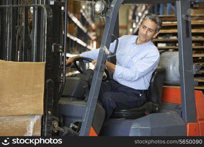 Man Driving Fork Lift Truck In Warehouse