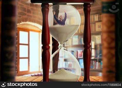 Man drowning inside an hourglass, deadline concept, bookshelf in the office on background. Man drowning inside an hourglass, deadline concept