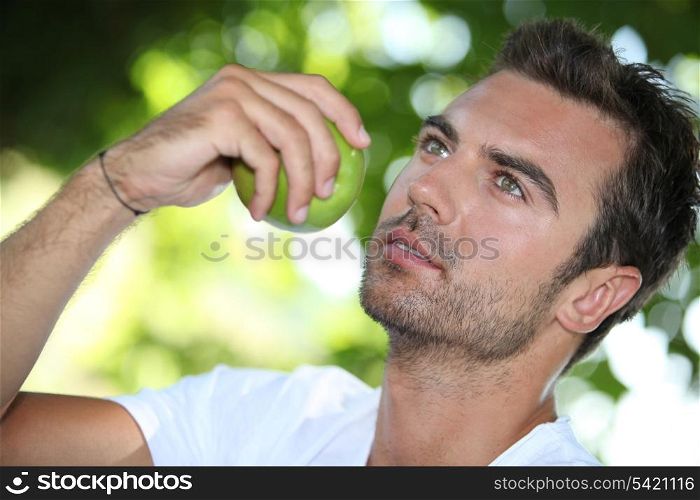 Man eating an apple under a tree