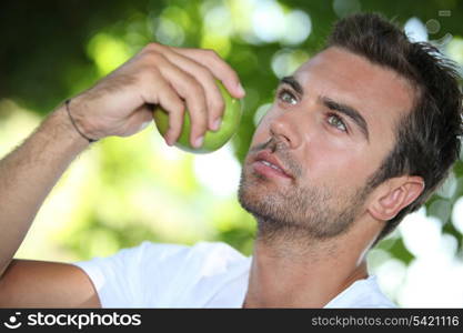 Man eating an apple under a tree