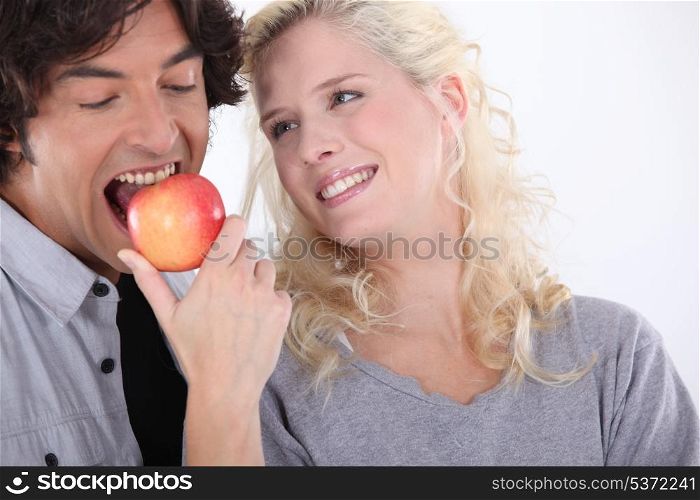 Man eating apple next to smiling woman