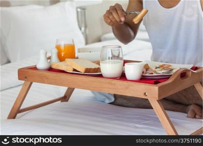 Man eating breakfast on tray in bed