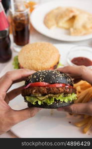 Man eating burgers at table, closeup photo