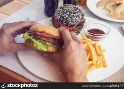 Man eating burgers at table, pov view