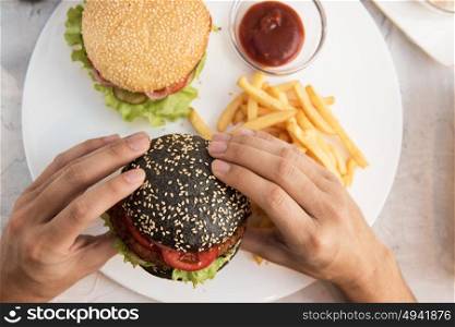 Man eating burgers. Man eating burgers at table, closeup photo