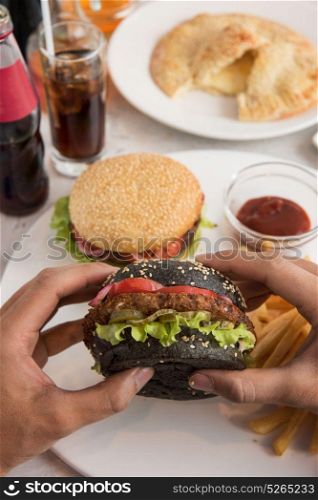 Man eating burgers. Man eating burgers at table, closeup photo