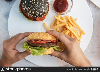 Man eating burgers. Man eating burgers at table, pov view