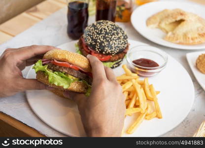 Man eating burgers. Man eating burgers at table, pov view